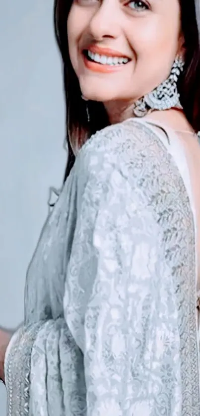 Elegant woman wearing a white lace saree, smiling softly.