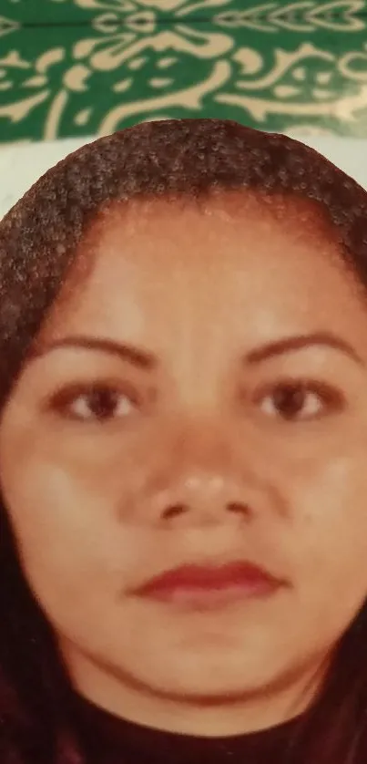 Close-up portrait of a woman against a decorative green background.