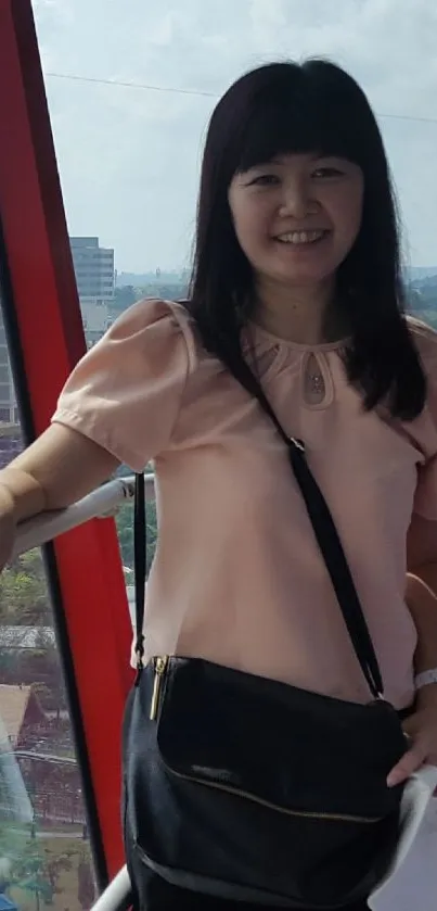 Woman in a pink blouse smiling in front of a scenic view.