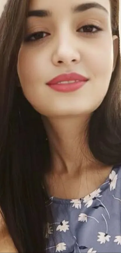 Portrait of a woman with long dark hair, vibrant lipstick, and floral top.