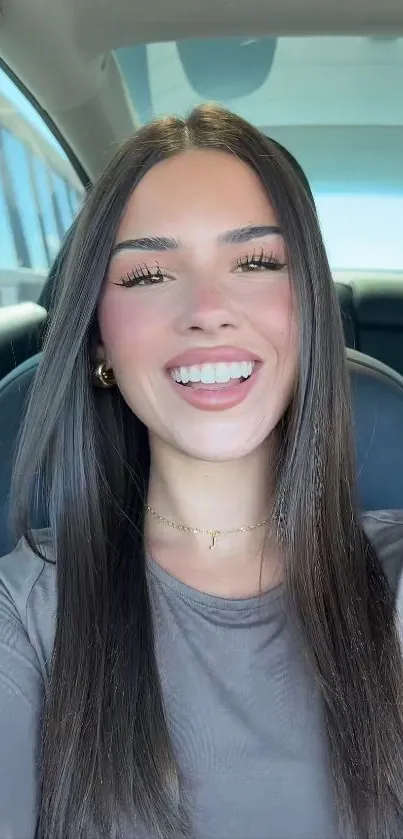 Smiling woman with long hair in a car, exuding elegance.