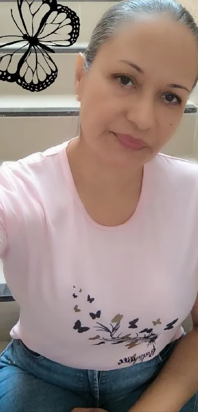 Woman in pink shirt with butterfly design on stairs.