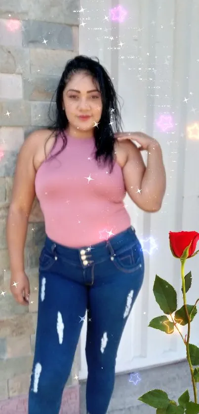 Woman in pink top and jeans posing with a red rose.