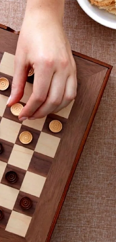 Hand playing a wooden board game on an elegant setup.