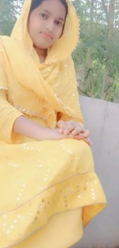 Woman in elegant yellow dress seated outdoors