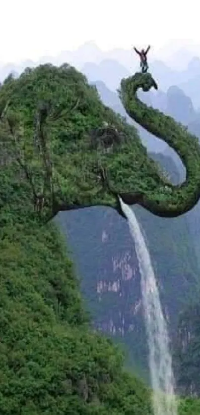 Elephant-shaped mountain with waterfall in lush green scenery.