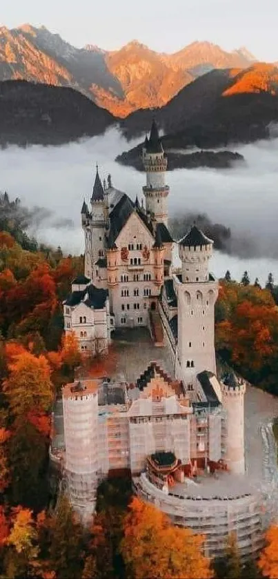 Majestic castle surrounded by autumn trees with misty mountain backdrop.