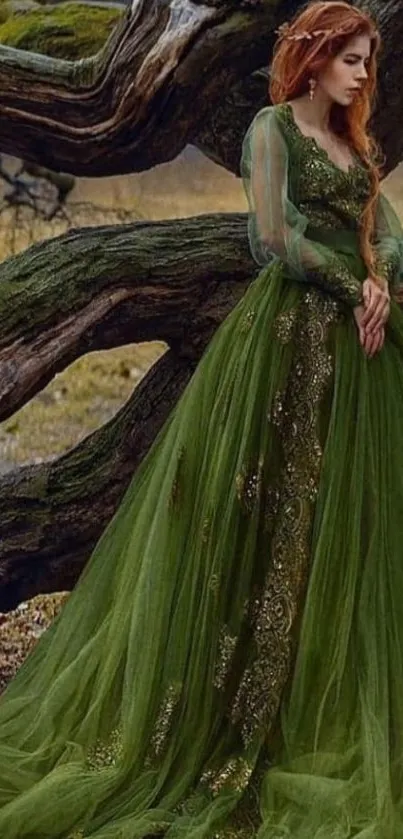 Woman in long green dress standing by a tree in the forest.