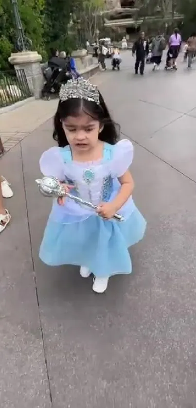 Little princess in a blue dress and tiara walking with a scepter.