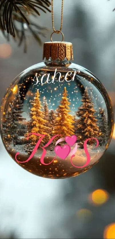 Christmas ornament with snowy forest scene inside, hanging on tree.