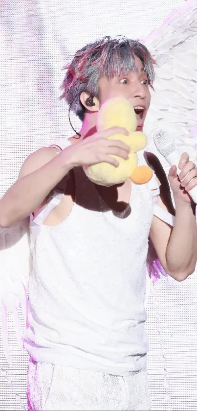 Performer with angel wings holding a plush toy on stage.