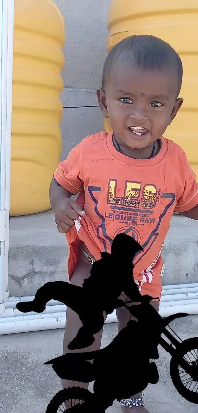 Child smiling with motorcycle silhouette in vibrant setting.