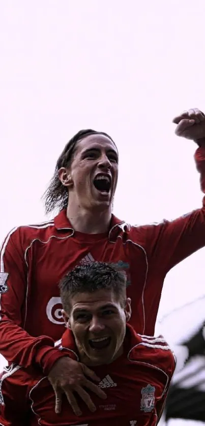 Two jubilant soccer players in red jerseys celebrating victory.