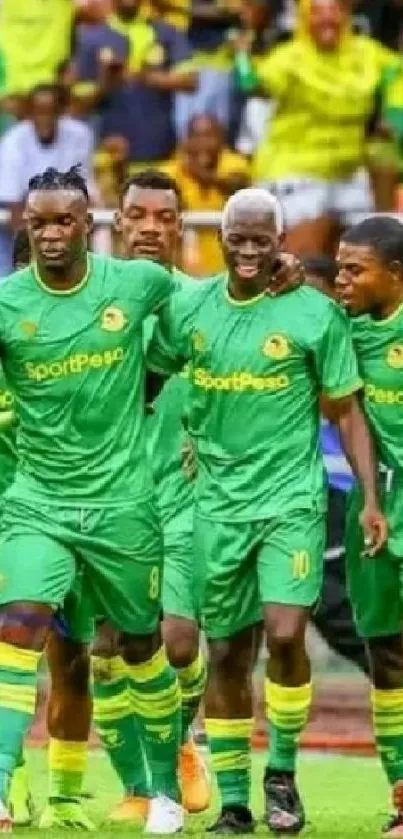 Soccer team in green uniforms celebrating on the field.