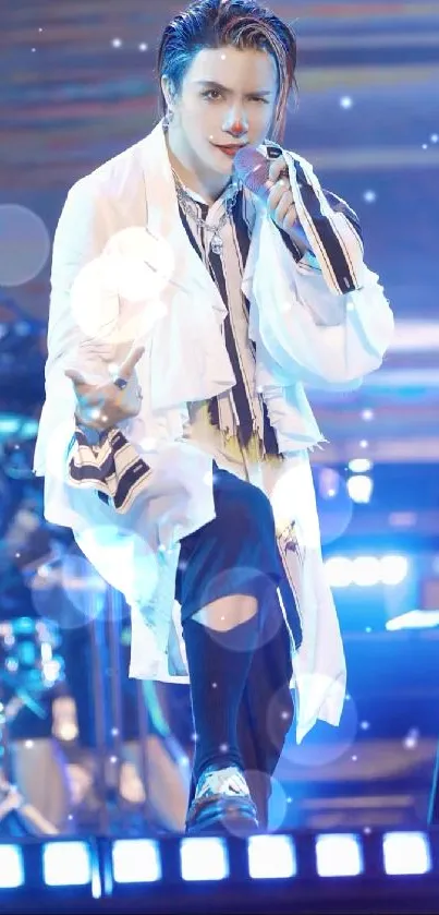 Performer on stage with blue lighting, wearing a white jacket.