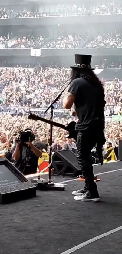 Musician performing on stage with a huge crowd in view.