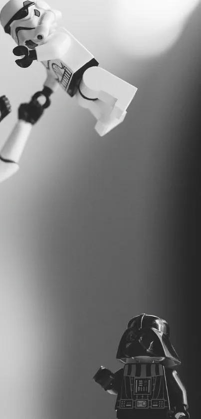 Monochrome scene with Stormtrooper lifting another toy, Darth Vader in background.