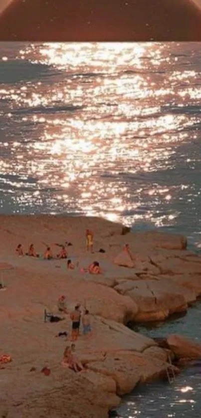 Sunset over a rocky beach with shimmering water reflections.