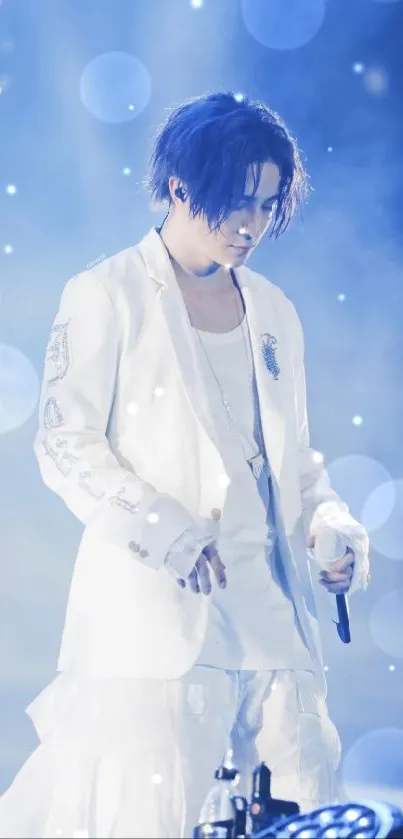 Performer in white suit on stage with blue lighting backdrop.