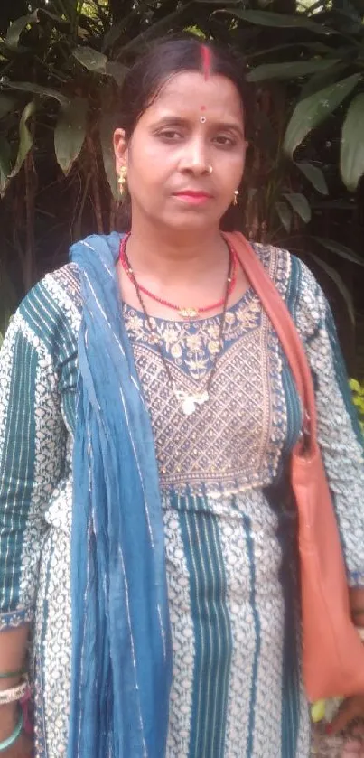 Woman in ethnic attire with green foliage background.