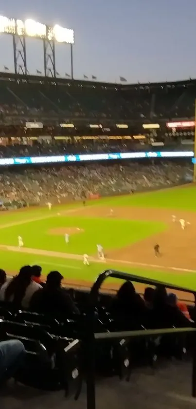 Baseball game at dusk with stadium lights and crowd.