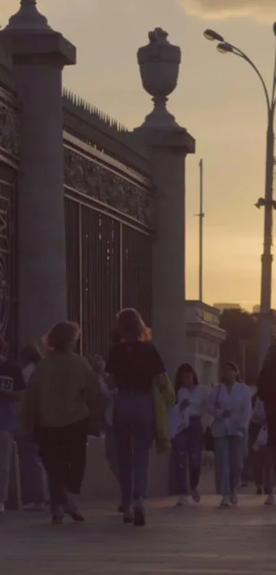 People walking near a gate at city sunset.