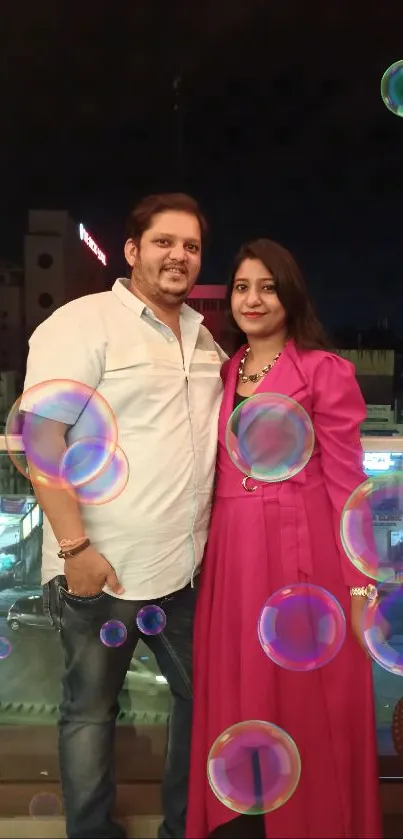 Couple enjoying a rooftop city view at night with vibrant lights in the background.