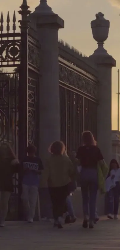 People walking by historic gates at sunset.