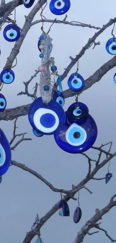 Evil eye charms hanging on branches against a serene sky.