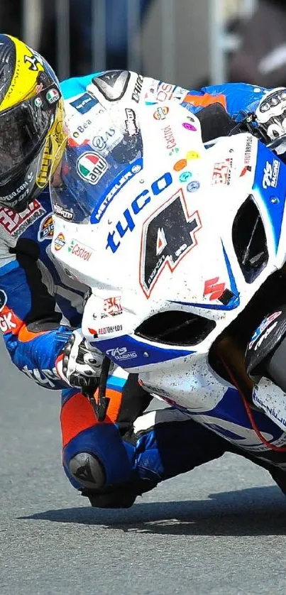 Motorcyclist racing on a track with a white and blue bike, leaning into a turn.