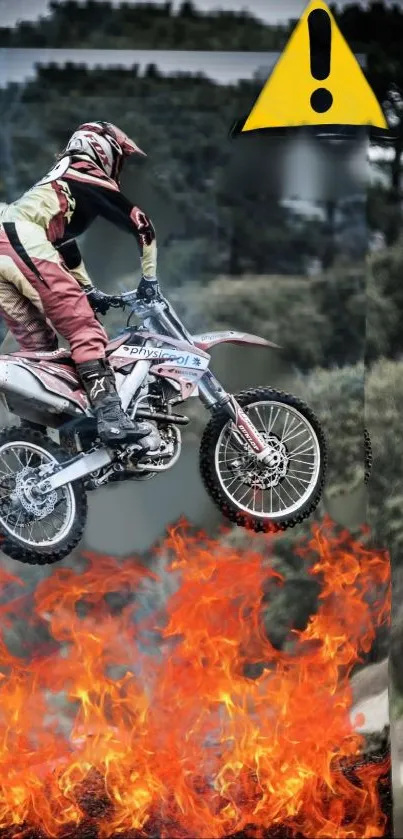 Motorcycle stunt rider jumps through flames with a warning sign overhead.