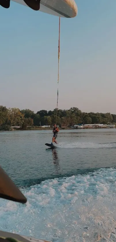 Wakeboarder gliding over a lake during sunset with scenic background.