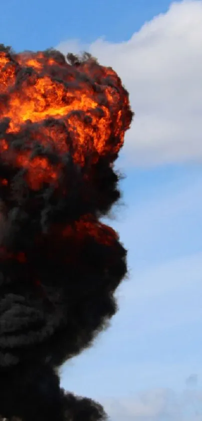 Dynamic explosion with fire and smoke against a blue sky.