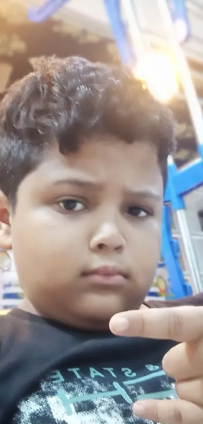 Young boy striking a pose indoors on a vibrant wallpaper.