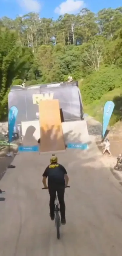 BMX biker approaching a stunt ramp in a lush outdoor setting.