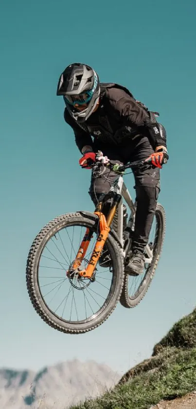 Cyclist performing a jump on a mountain trail with scenic backdrop.