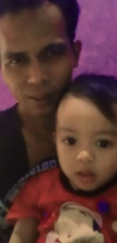 Father holding child with purple background.