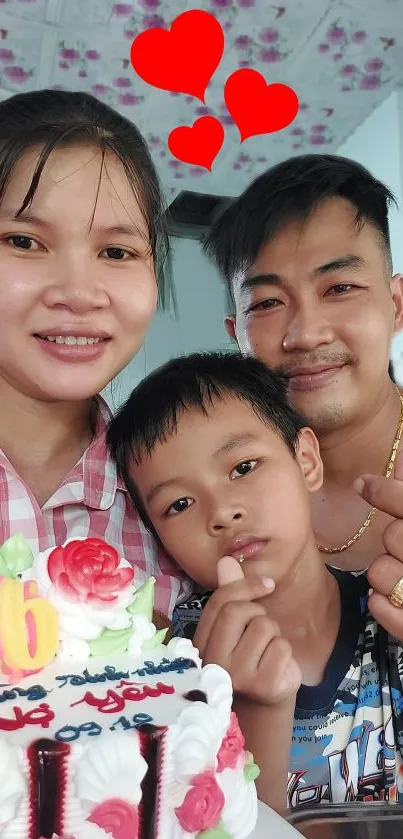 Smiling family celebrating with cake and heart decorations.