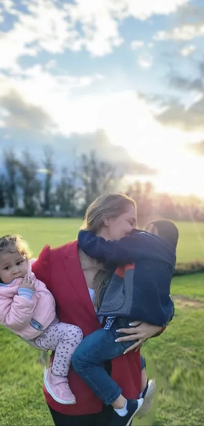 Mother holding children at sunset in a green field.