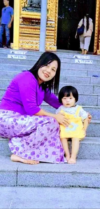 Mother and child on stone steps, vibrant colors.