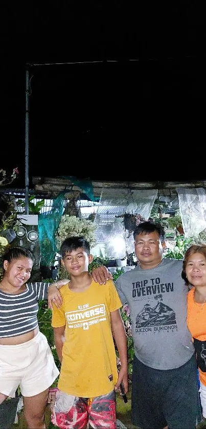 Happy family posing at night in a garden setting, creating a lively wallpaper.