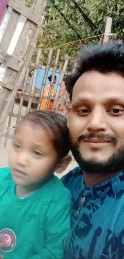 A father and child enjoying a moment outdoors with greenery in the background.