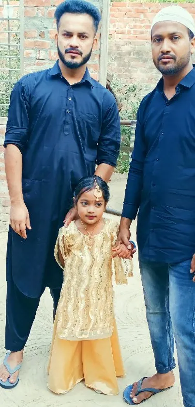 Family portrait with child in golden dress and men in blue attire.