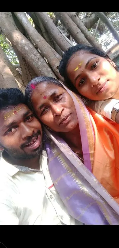 Family in traditional attire under a banyan tree.