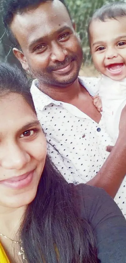 Happy family with baby smiling for a photo in natural setting.