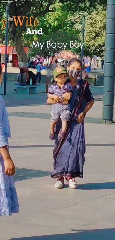 Mother carrying child in a park with trees.