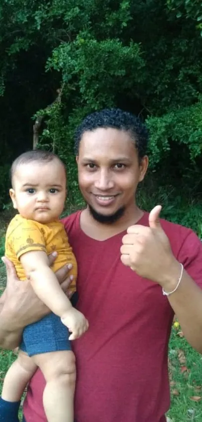 Father holding baby in lush green park.