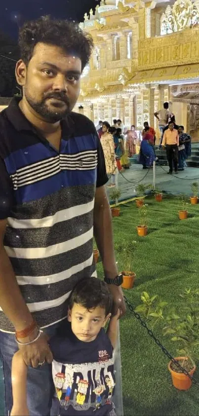 Father and child enjoying a night festival with illuminated architecture.