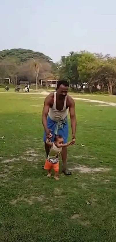 Father guides child walking on grass in park.