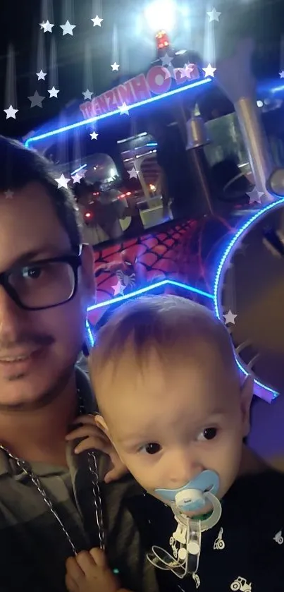 Father and child enjoying neon train ride at night.